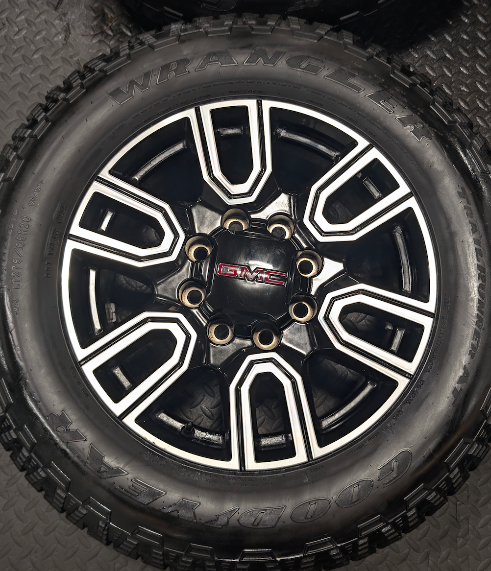 OEM 20” GMC Sierra AT4 2500HD / 3500HD Wheels with Black & Machined Finish wrapped in LT275/65R20 Goodyear Wrangler TrailRunner A/T tires.