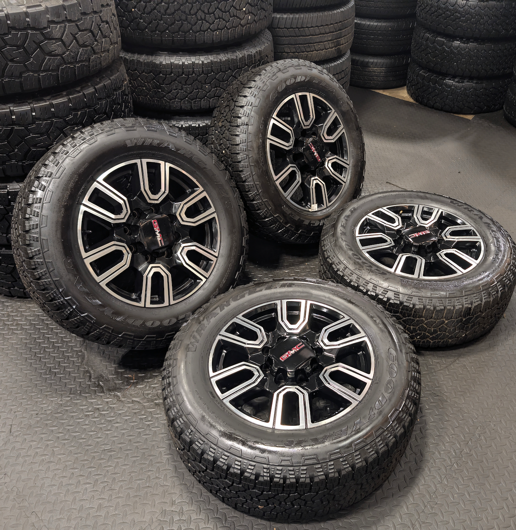 OEM 20” GMC Sierra AT4 2500HD / 3500HD Wheels with Black & Machined Finish wrapped in LT275/65R20 Goodyear Wrangler TrailRunner A/T tires.