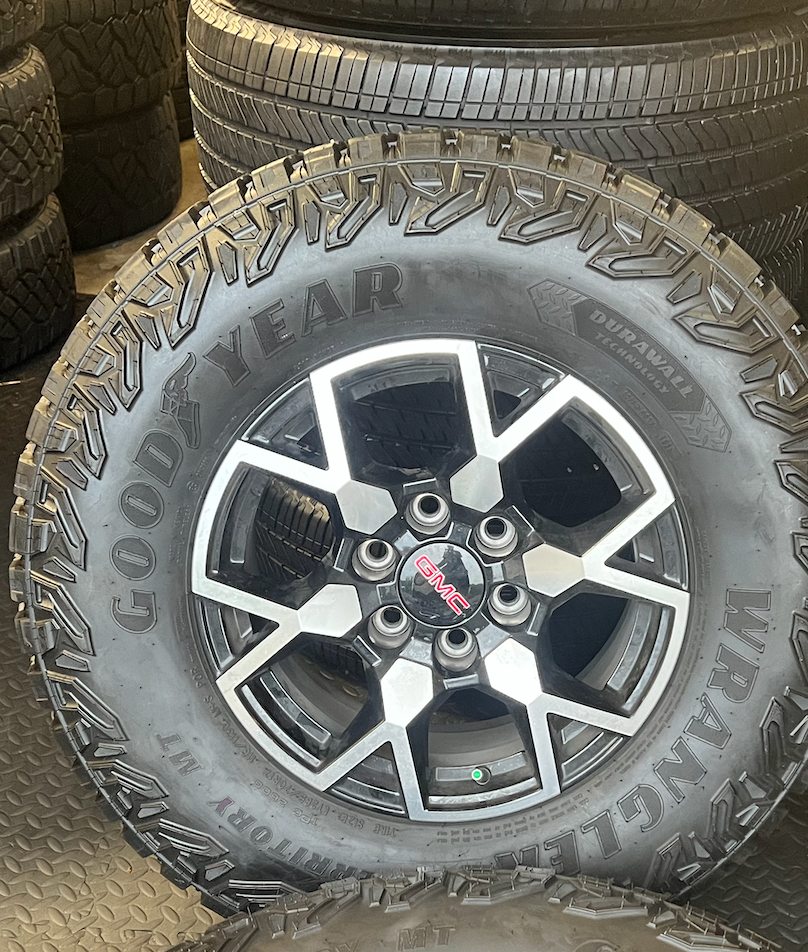 OEM 17”  Wheels with Black & Machined Finish wrapped in Goodyear Wrangler Territory M/T tires.