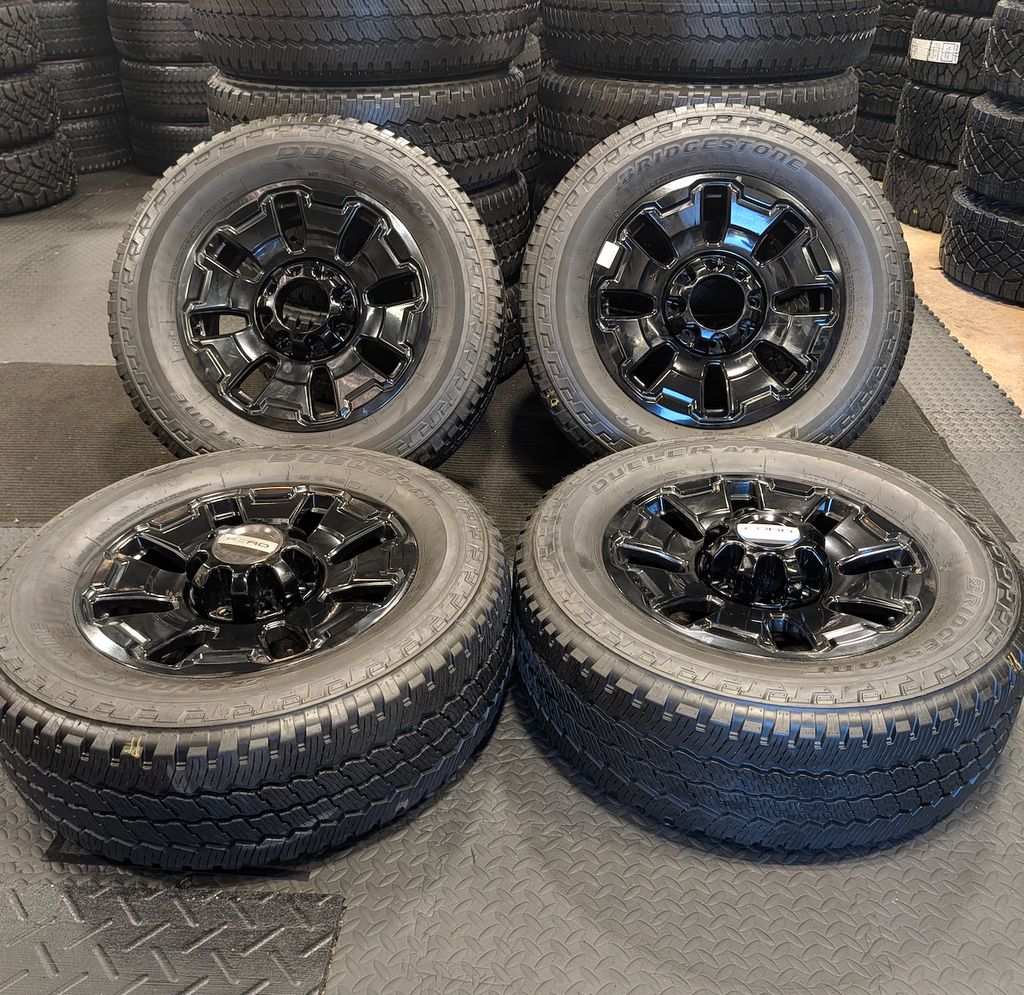 OEM 18” Ford F-250 / F-350 Tremor Wheels with Gloss Black Finish wrapped in Bridgestone Dueler A/T tires.