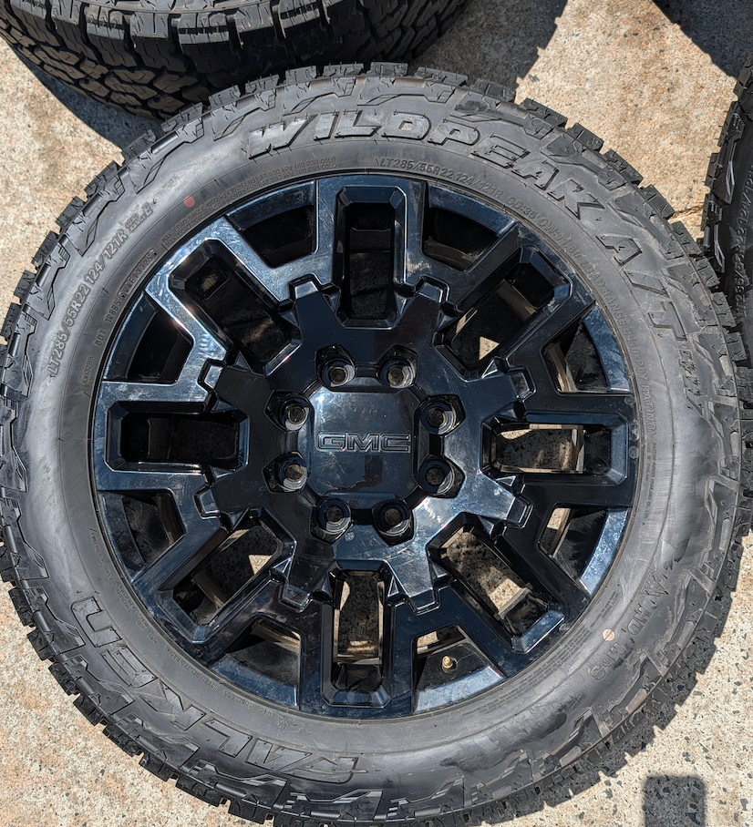 OEM 22” Gloss Black GMC HD Wheels with Split-Spoke Design wrapped in LT285/55R22 Falken Wildpeak A/T4W tires.