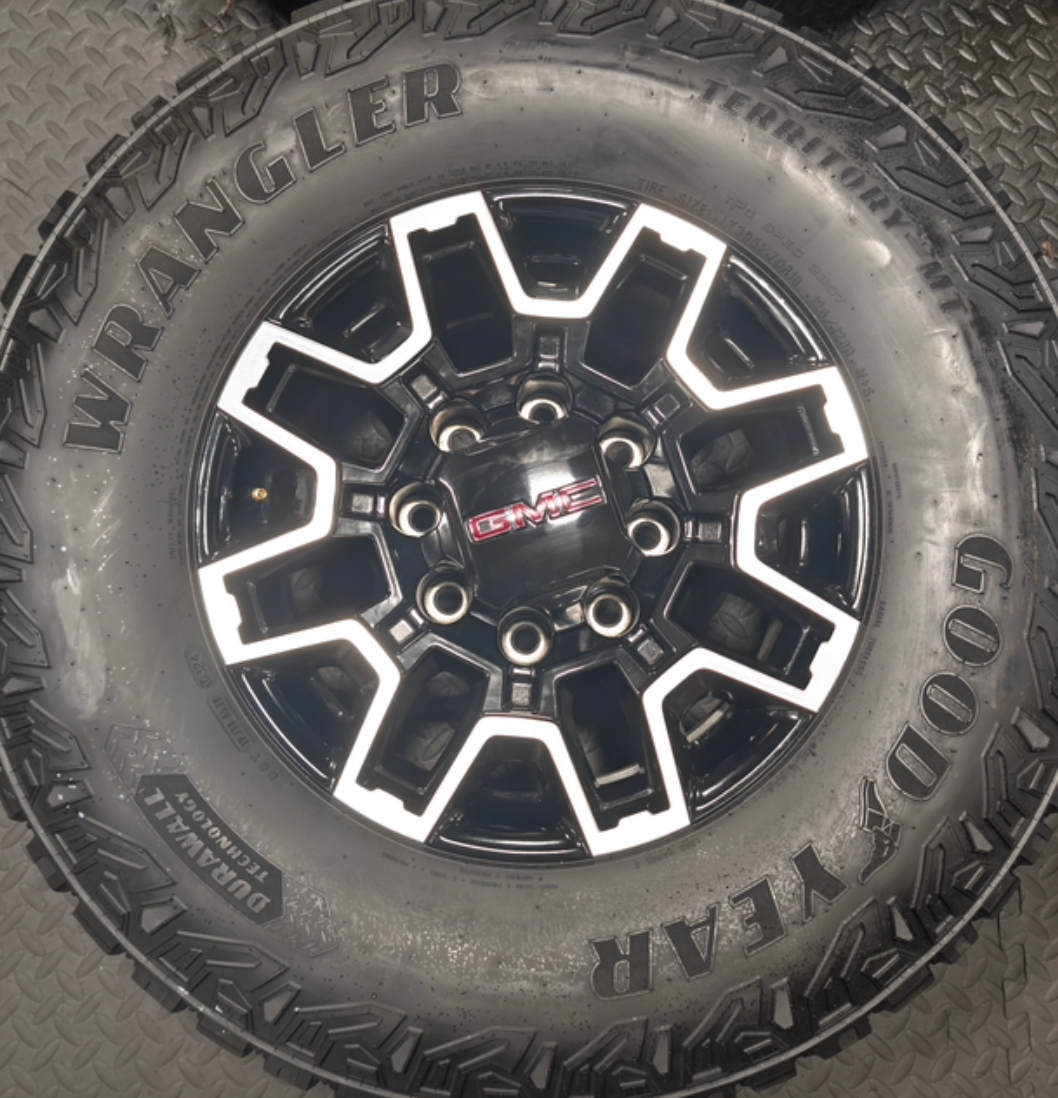 OEM 18” GMC Sierra 2500HD AT4X Black Wheels wrapped in Goodyear Wrangler Territory M/T tires.
