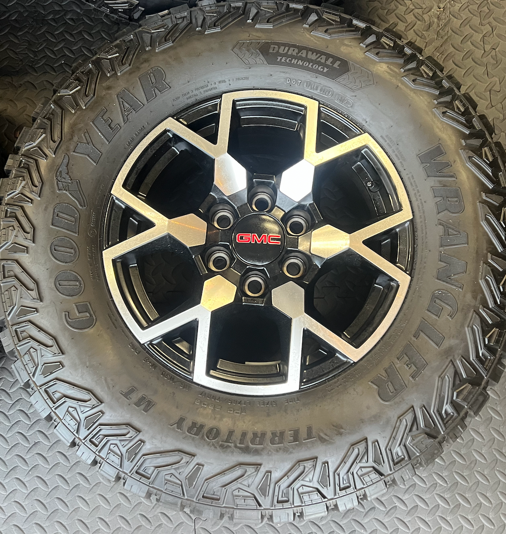 OEM 17”  Wheels with Black & Machined Finish wrapped in Goodyear Wrangler Territory M/T tires.