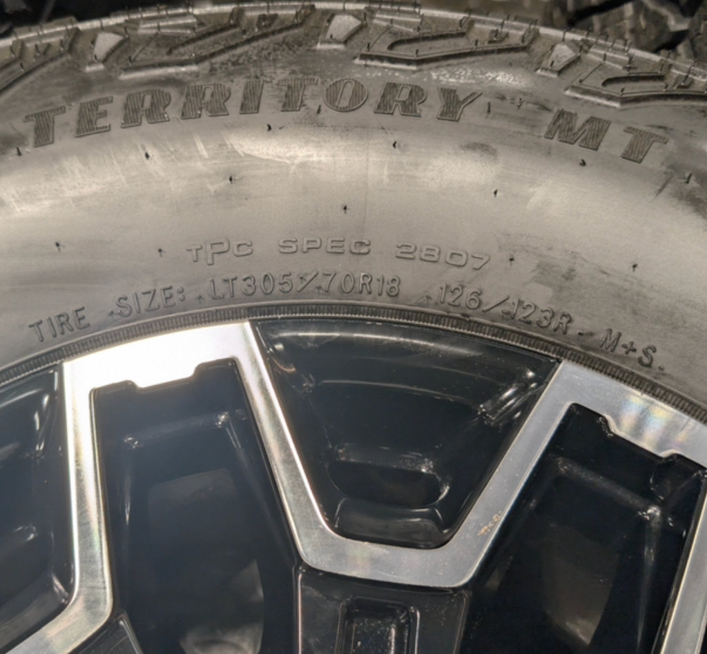 OEM 18” GMC Sierra 2500HD AT4X Black Wheels wrapped in Goodyear Wrangler Territory M/T tires.