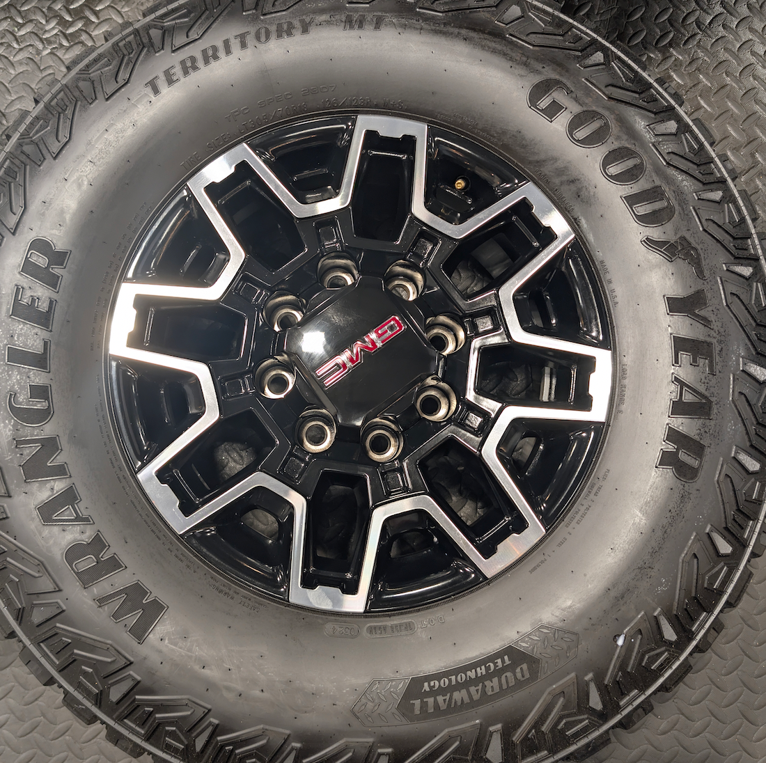 OEM 18” GMC Sierra 2500HD AT4X Black Wheels wrapped in Goodyear Wrangler Territory M/T tires.