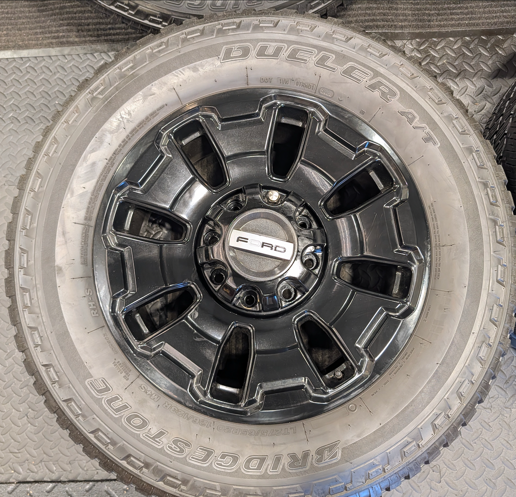 OEM 18” Ford F-250 / F-350 Tremor Wheels with Gloss Black Finish wrapped in Bridgestone Dueler A/T tires.