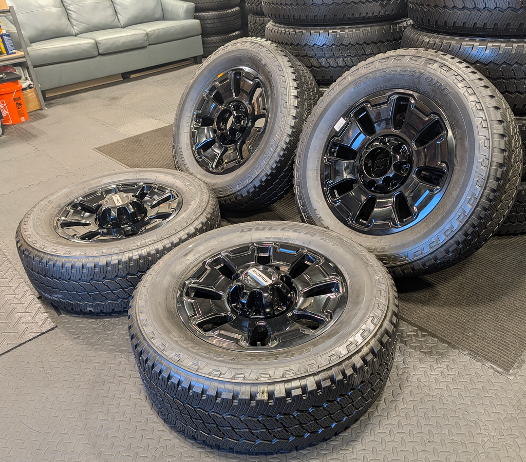 OEM 18” Ford F-250 / F-350 Tremor Wheels with Gloss Black Finish wrapped in Bridgestone Dueler A/T tires.