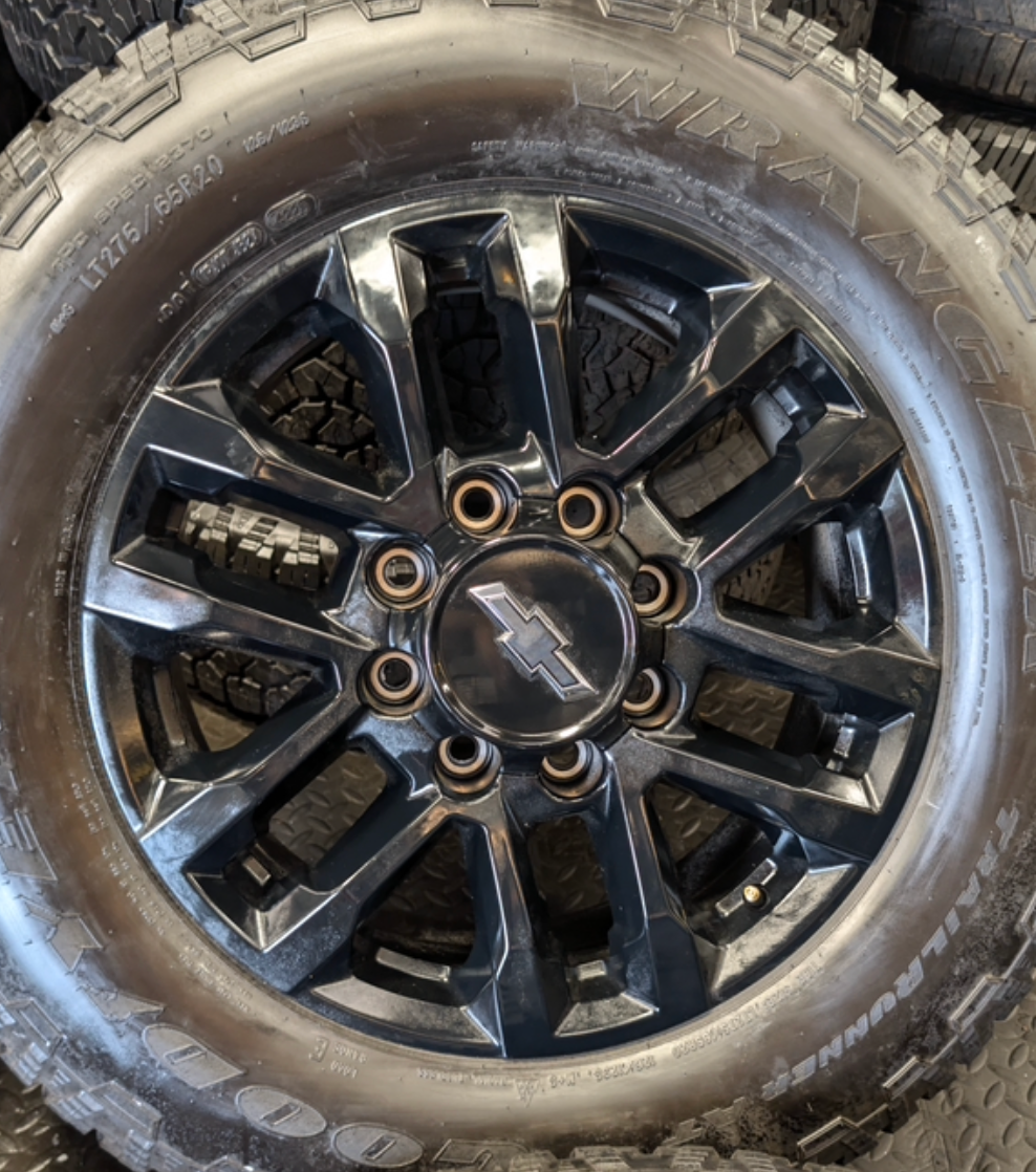 OEM 20” Gloss Black Chevrolet Silverado / GMC Sierra 2500HD & 3500HD Wheels wrapped in LT275/65R20 Goodyear Wrangler TrailRunner A/T tires.