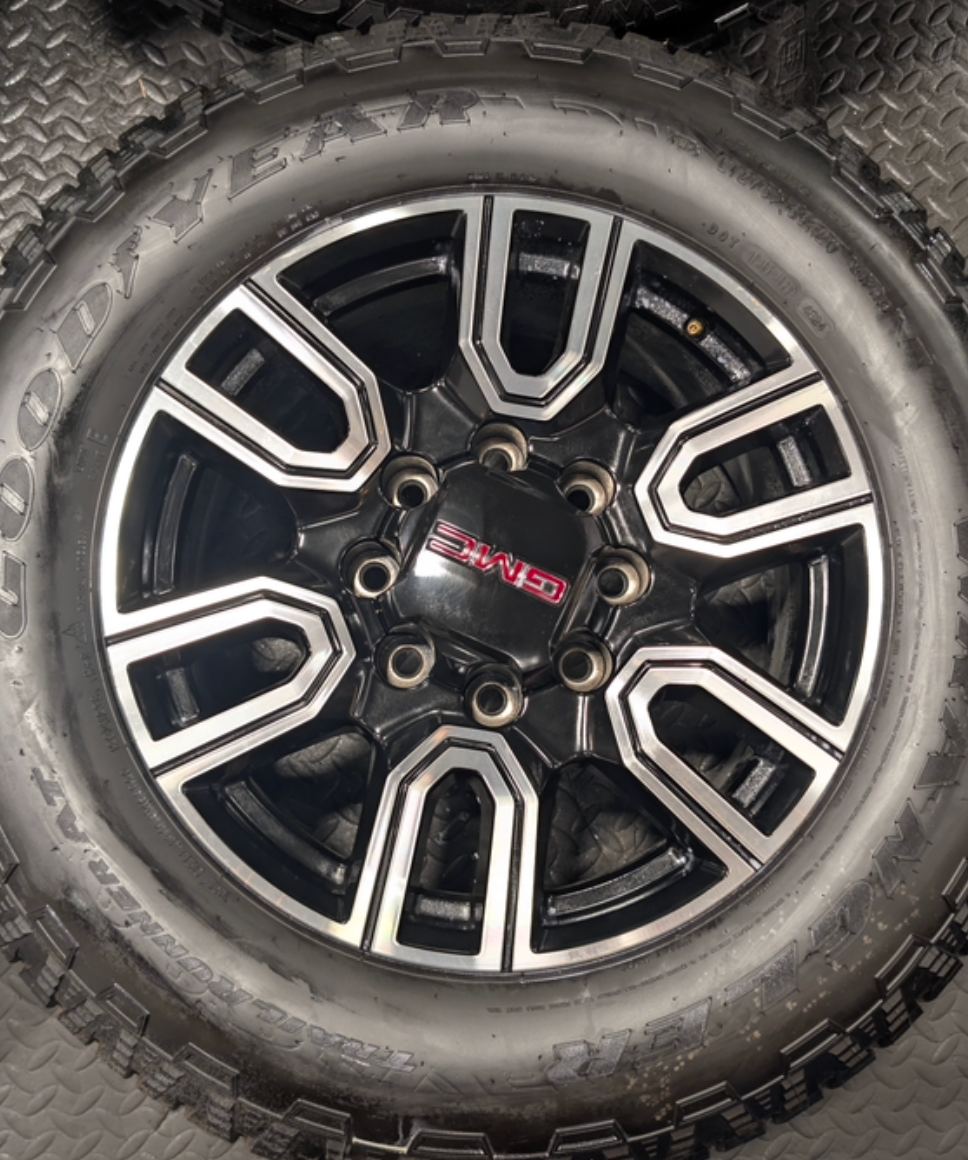 OEM 20” GMC Sierra AT4 2500HD / 3500HD Wheels with Black & Machined Finish wrapped in LT275/65R20 Goodyear Wrangler TrailRunner A/T tires.
