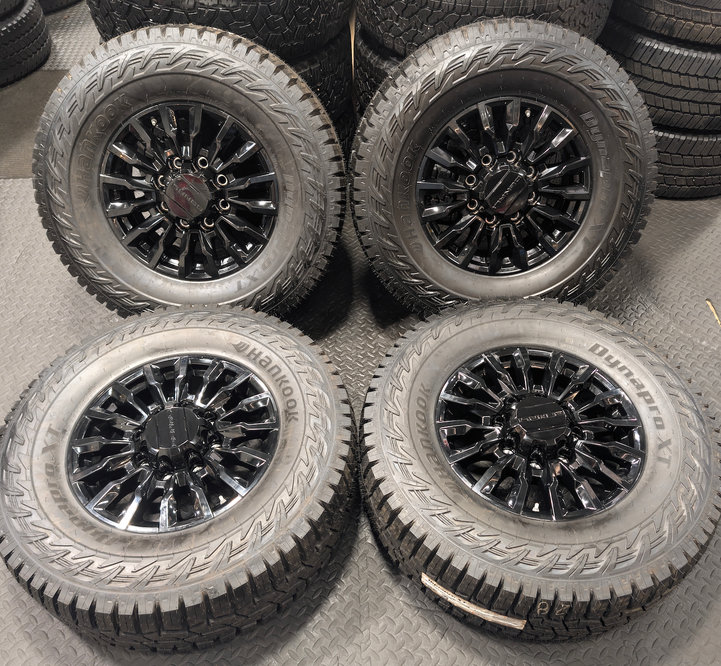 OEM 18” Gloss Black GMC Sierra / Chevrolet Silverado 2500HD & 3500HD Wheels wrapped in Hankook Dynapro XT tires.