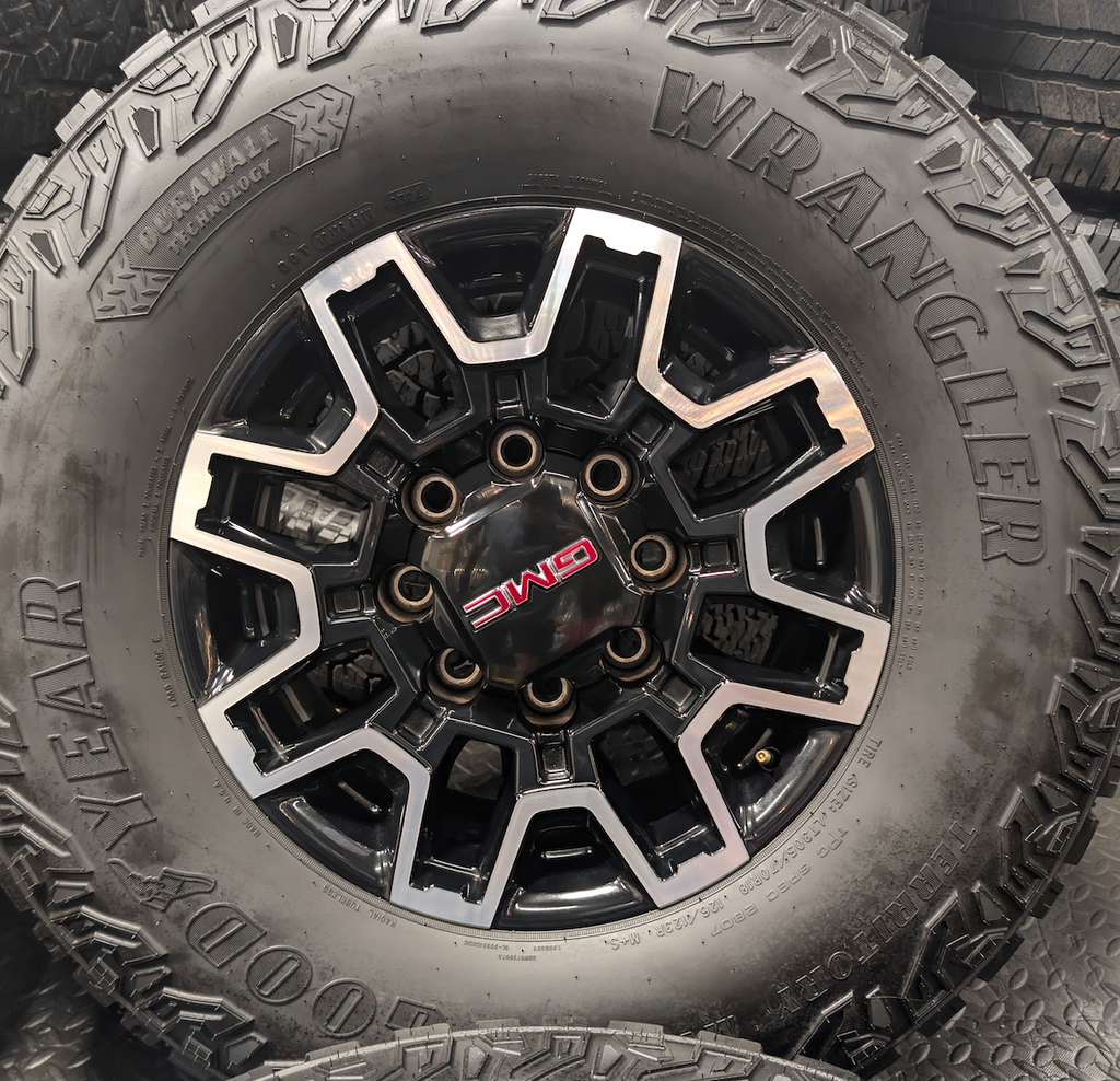 OEM 18” GMC Sierra 2500HD AT4X Black Wheels wrapped in Goodyear Wrangler Territory M/T tires.