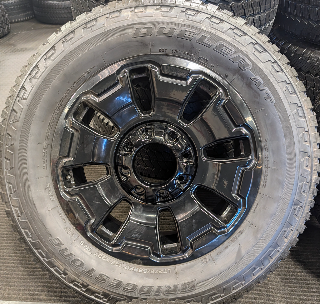 OEM 18” Ford F-250 / F-350 Tremor Wheels with Gloss Black Finish wrapped in Bridgestone Dueler A/T tires.