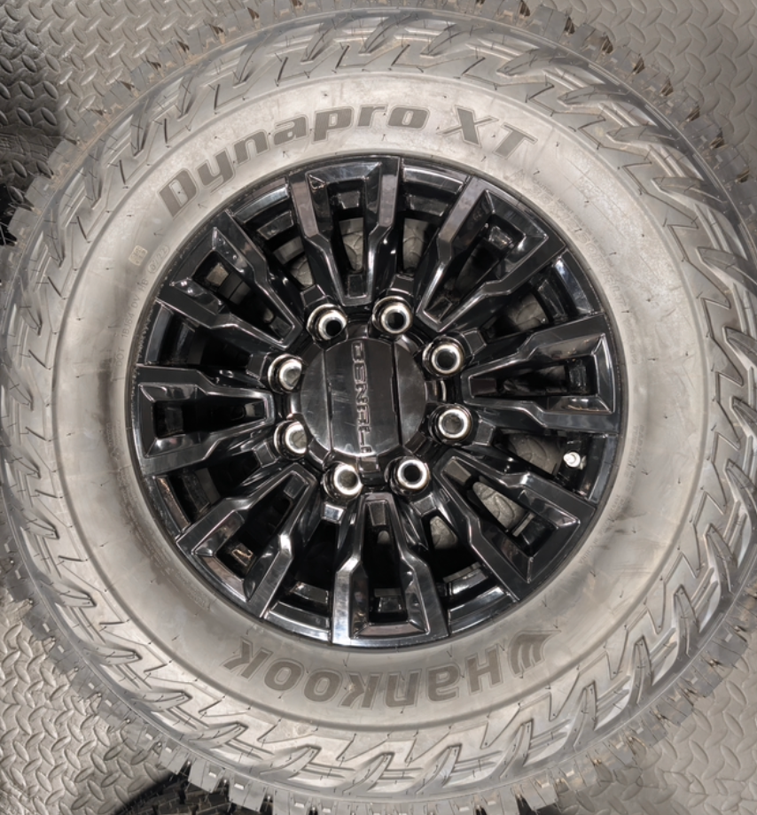 OEM 18” Gloss Black GMC Sierra / Chevrolet Silverado 2500HD & 3500HD Wheels wrapped in Hankook Dynapro XT tires.